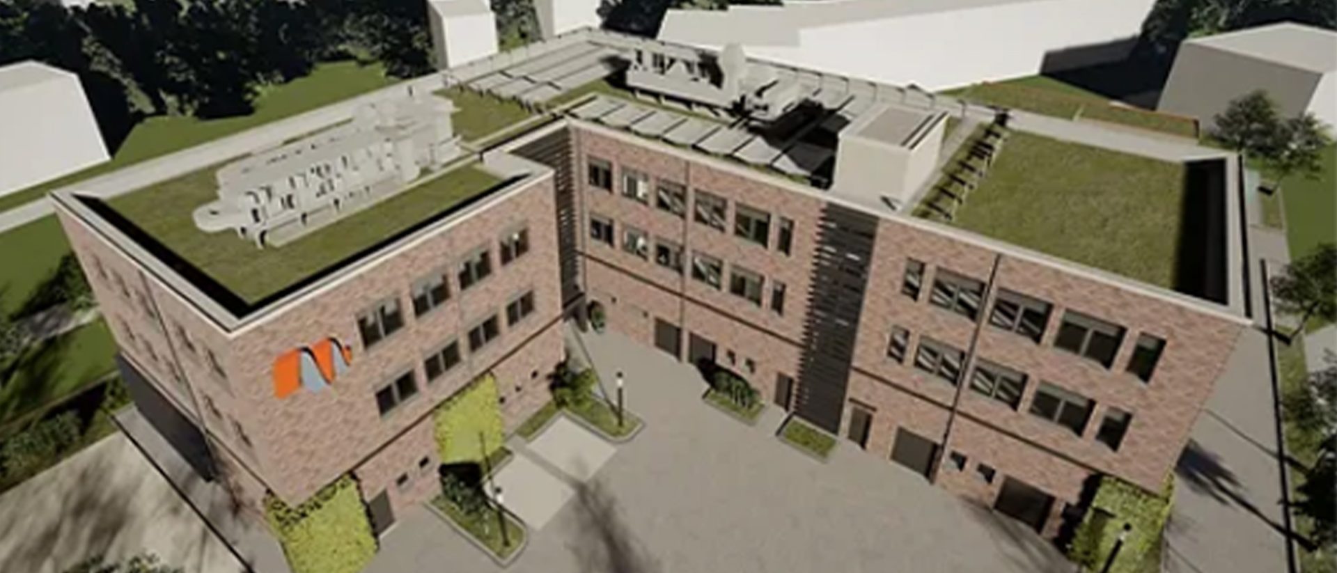 Aerial view of a modern brick building with green roofs and rooftop equipment, surrounded by landscaping and pathways.