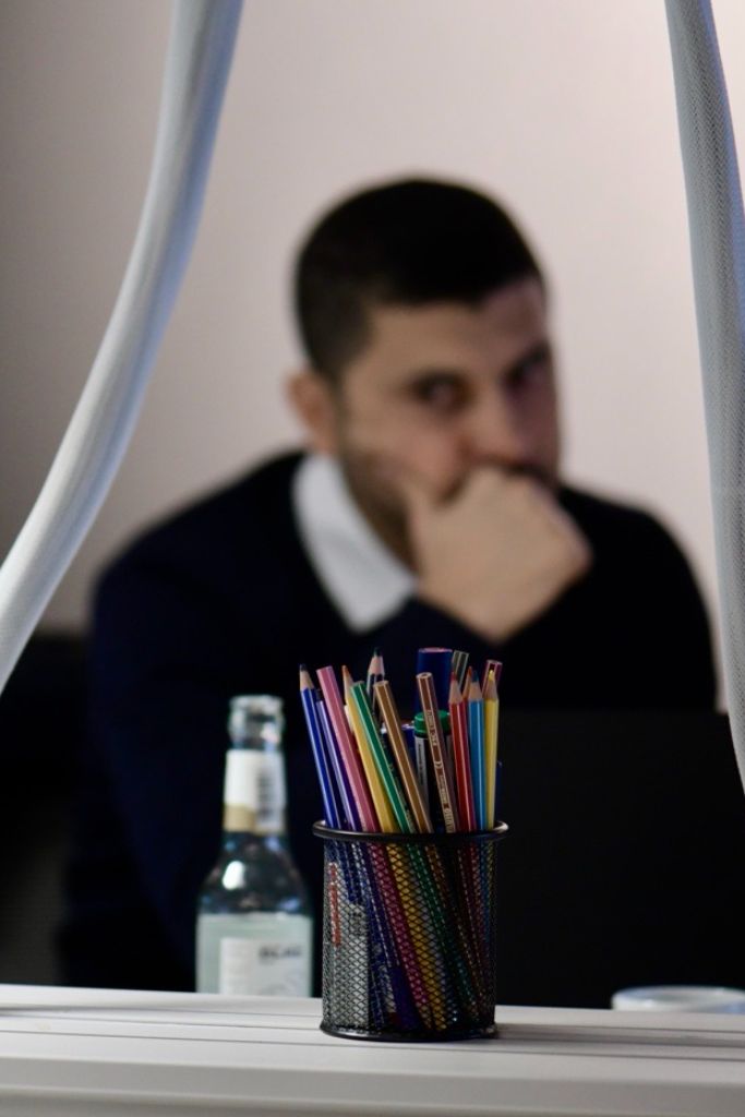 A man sits in the background with his hand on his chin, while a pencil holder filled with colored pencils is in focus in the foreground at the Offshore Structural Design Workshop JBO.